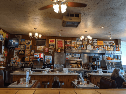 A retro diner interior with a counter, vintage advertisements, and a cozy atmosphere.