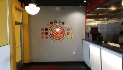 Interior of a restaurant featuring a logo on the wall and a counter with a menu display.