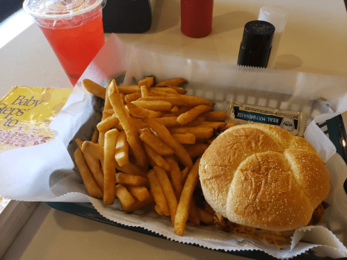 A plate with a sandwich and fries, accompanied by a drink and condiments on the side.