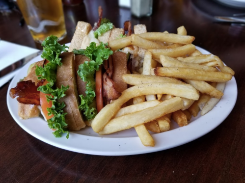 A plate with a sandwich featuring bacon, lettuce, and tomato, accompanied by a side of crispy French fries.