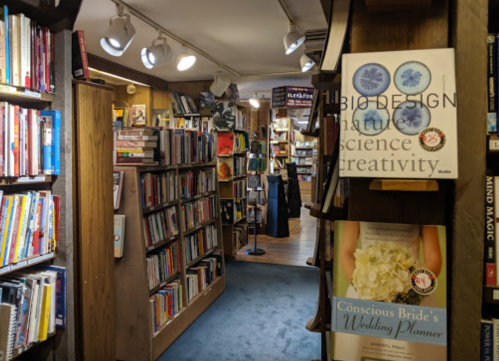 A cozy bookstore aisle lined with bookshelves, featuring titles on science and wedding planning. Soft lighting enhances the atmosphere.