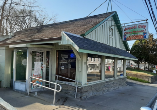 Exterior of Jewett City Pizza Palace, a small restaurant with a green and white facade and a sign above the entrance.