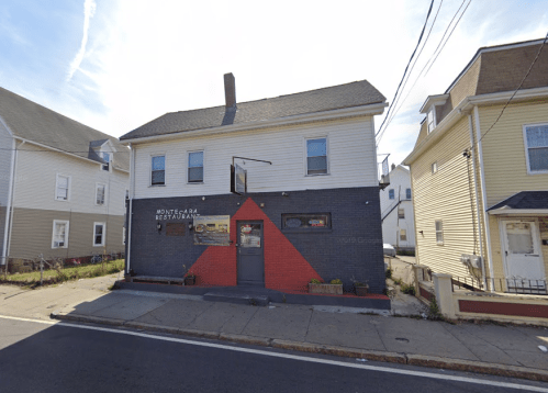 A two-story restaurant with a red and gray exterior, located on a street with nearby residential buildings.