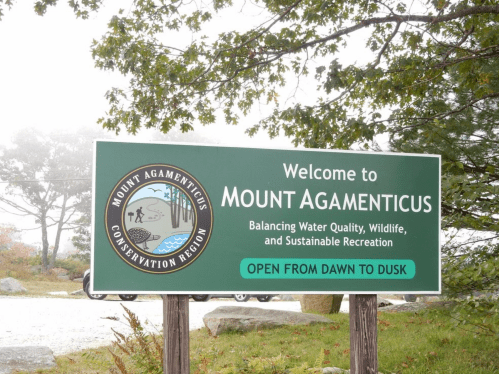 Welcome sign for Mount Agamenticus Conservation Region, highlighting water quality, wildlife, and recreation. Open dawn to dusk.