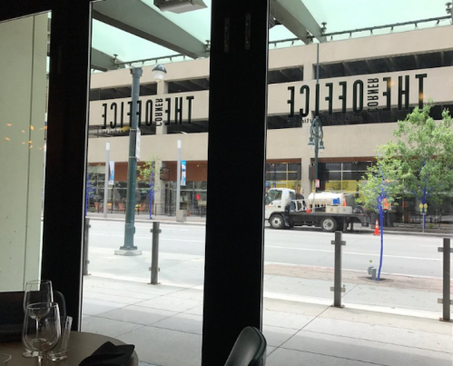 View from inside a restaurant showing large windows, street, and reflections of nearby buildings.