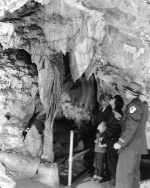 A family and a park ranger explore a cave with stalactites and rock formations.