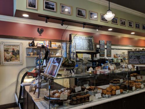 Cozy café interior with a display of pastries, a chalkboard menu, and framed photos on the walls.