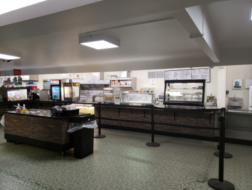 A spacious, empty food counter area with display cases, a menu board, and a tiled floor.