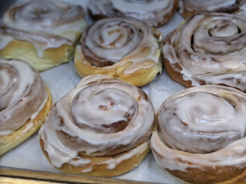 Freshly baked cinnamon rolls with creamy icing, arranged on a tray.