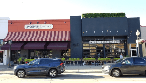 Exterior view of two restaurants: Pop's Italian with red awning and a wine and beer garden with outdoor seating.