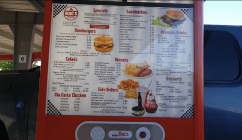 Menu board featuring burgers, sandwiches, salads, drinks, and desserts at Mac's restaurant. Prices listed for each item.