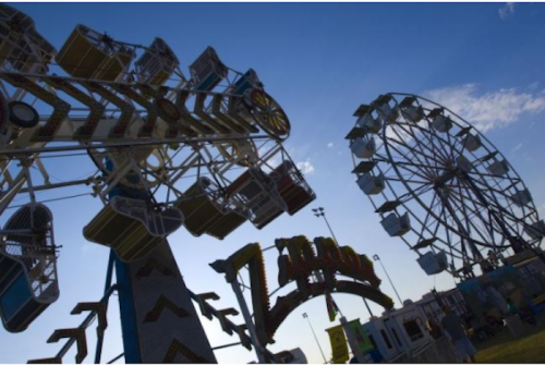 A vibrant amusement park scene featuring a Ferris wheel and a thrilling ride against a blue sky.