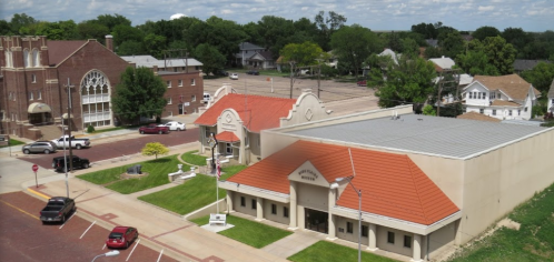 Aerial view of a small town featuring buildings, green lawns, and a clear blue sky.