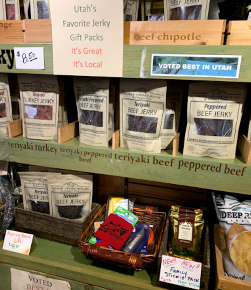 Display of various jerky products and gift packs labeled "Utah's Favorite Jerky" with prices and promotional signs.