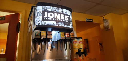 A soda fountain machine featuring Jones Cane Sugar Soda with various drink options displayed.