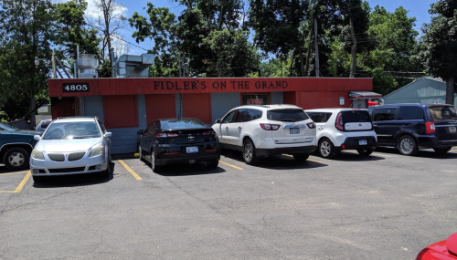 A restaurant named "Fidler's on the Grand" with several parked cars in front and trees in the background.