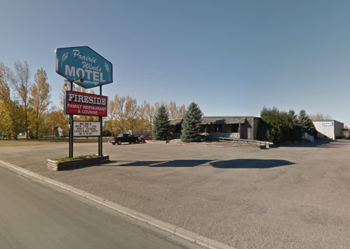 Sign for Prairie Winds Motel and Fireside Family Restaurant, with trees and a clear blue sky in the background.