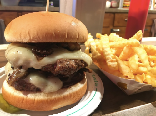 A juicy double cheeseburger with melted cheese and mushrooms, served with a side of crispy crinkle-cut fries.