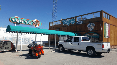 A pizza restaurant named Tony's with a green awning, a motorcycle parked outside, and a white pickup truck.