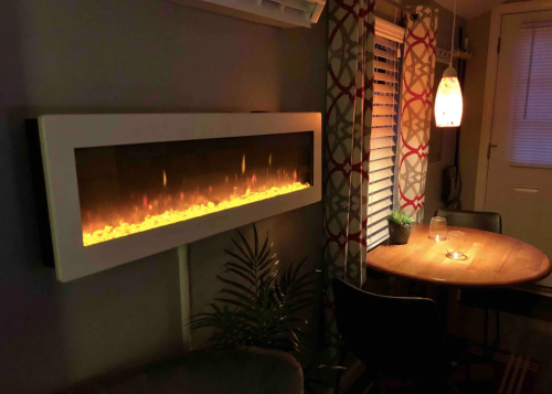A modern electric fireplace with glowing flames, beside a small dining table and decorative plants in a cozy room.