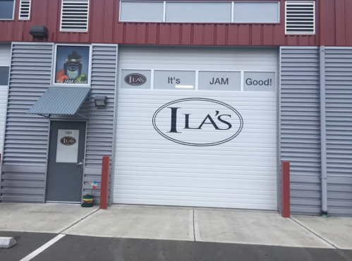 Exterior of a building with a large sign reading "JLA's" and the phrase "It's JAM Good!" on the garage door.