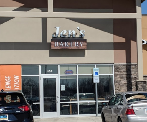 Sign for "Jen's Bakery" on a storefront with cars parked outside.