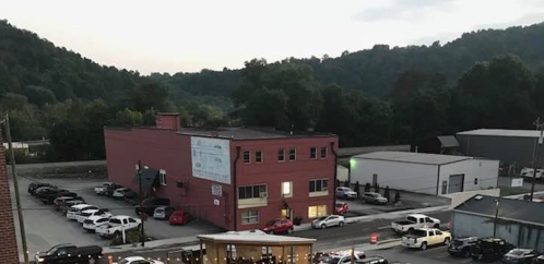 Aerial view of a pink building surrounded by cars, with hills in the background under a twilight sky.