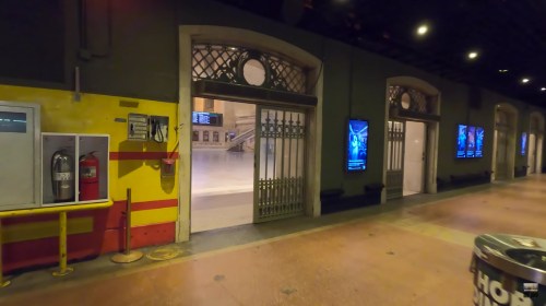 Interior of a train station with large doors, digital displays, and a clean, empty platform area.