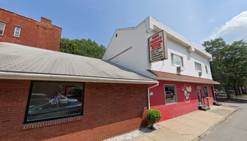 A red and white building with a sign for "Red Fort" and a nearby shop window displaying "Cat Tire." Clear blue sky above.