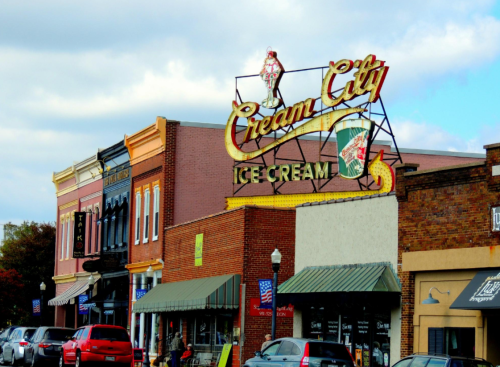 Colorful storefronts line a street, featuring a prominent vintage ice cream sign for "Cream City Ice Cream."