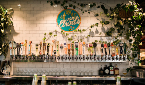 A wall of beer taps with various brands, surrounded by greenery and a sign that reads "von Ebrods."