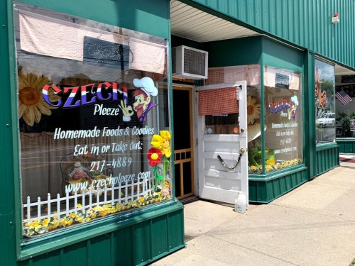 Exterior of a restaurant with colorful signage, featuring a chef and flowers, promoting homemade foods and takeout options.