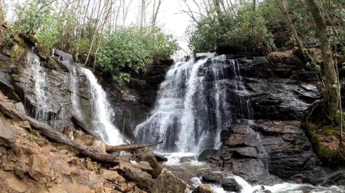 A serene waterfall cascading over rocky terrain, surrounded by lush greenery and trees.