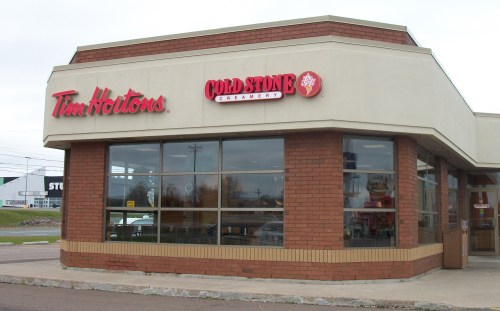 Exterior view of a Tim Hortons and Cold Stone Creamery storefront, featuring a brick facade and large windows.