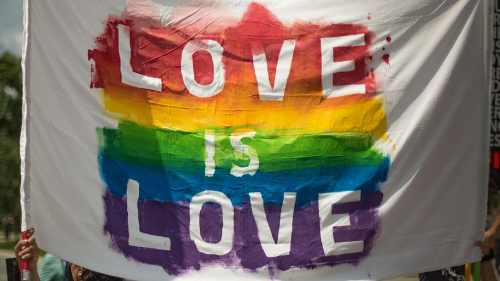 A colorful banner with the text "LOVE IS LOVE" in bold letters, featuring a rainbow background.