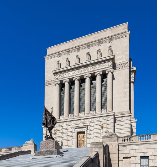 Indiana World War Memorial, a grand stone structure with columns and a statue, set against a clear blue sky.