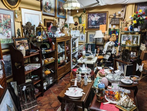 A cozy antique shop filled with various vintage items, including furniture, artwork, and decorative pieces.