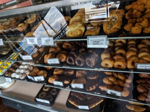 A display case filled with various baked goods, including donuts, pastries, and muffins.