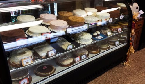 A display case filled with various cakes and desserts, showcasing a variety of flavors and styles.