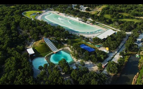 Aerial view of a water park featuring wave pools, slides, and lush greenery surrounding the area.
