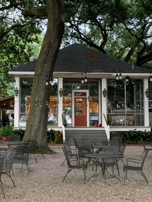 A charming gazebo-style building surrounded by trees, with outdoor seating and warm lights.