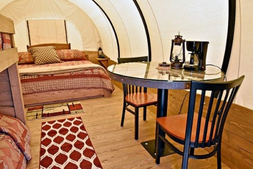 Cozy interior of a glamping tent featuring a bed, dining table, and rustic decor.