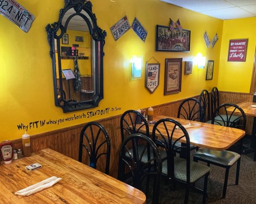 Cozy restaurant interior with yellow walls, wooden tables, and eclectic decor, featuring a quote by Dr. Seuss.