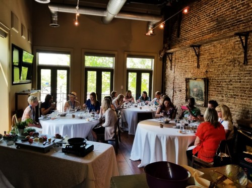 A group of people dining at a restaurant with large windows and exposed brick walls, engaged in conversation.