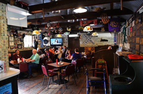 Cozy restaurant interior with wooden floors, vintage decor, and patrons enjoying meals at tables.