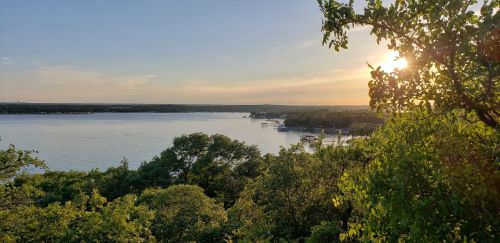 A serene lake view at sunset, surrounded by lush greenery and calm waters reflecting the golden light.