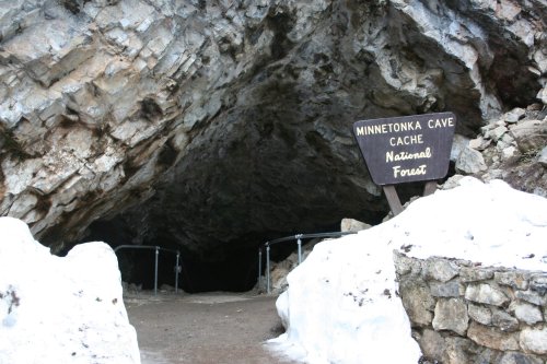 Entrance to Minnetonka Cave in Cache National Forest, surrounded by rocky terrain and snow.