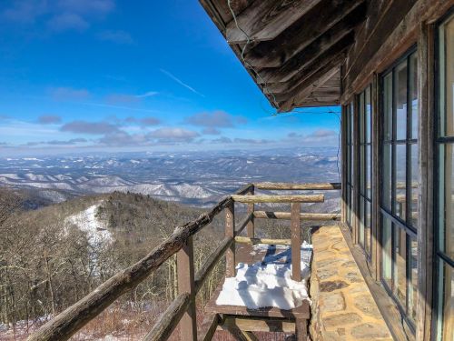 A scenic view from a wooden lookout, showcasing snow-covered mountains and a clear blue sky.