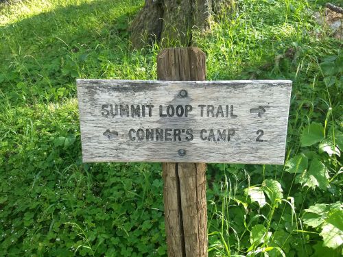 Wooden signpost indicating directions to Summit Loop Trail and Conner's Camp, with a distance of 2 miles.
