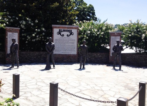 A stone plaza featuring five bronze statues of musicians, with a large sign reading "Alabama" in the background.